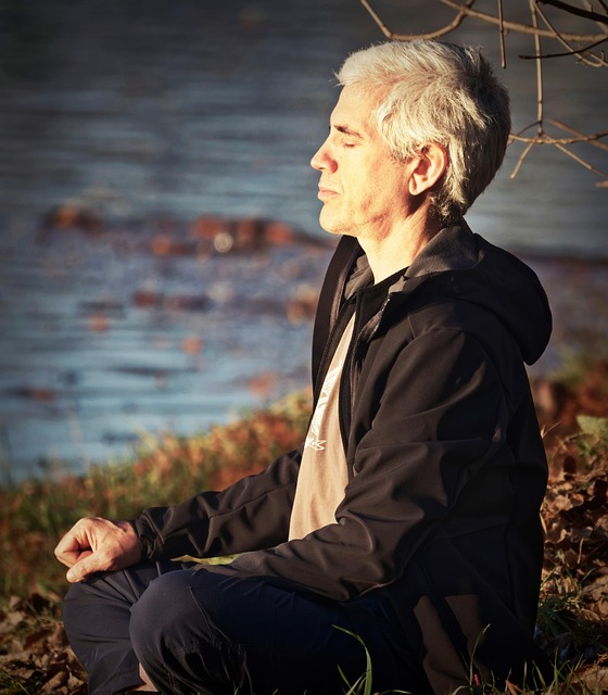 Homem de meia-idade meditando ao ar livre perto da natureza — prática de mindfulness para saúde mental após os 40